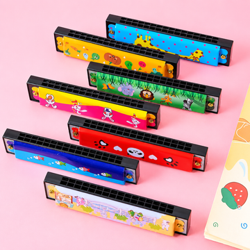 Seven colorful kid's harmonicas with cute cartoon animal prints lined up diagonally on a pastel pink background