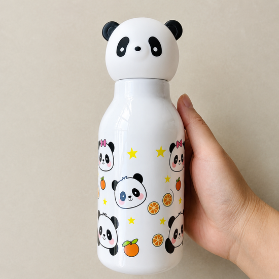 A hand holding a crisp white 500ml kids plastic water bottle covered in cute cartoon panda faces, yellow stars, and orange slices under a 3D panda cap