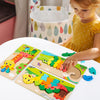 Toddler playing with a green crocodile wooden puzzle, fitting the segmented pieces into the board.