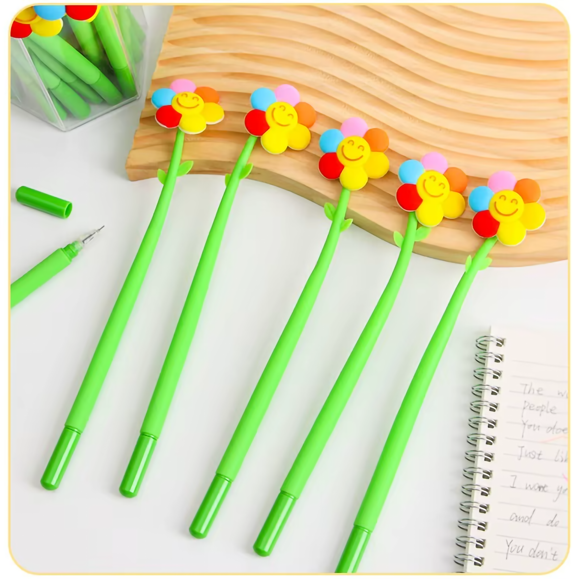 A collection of colorful flower shake gel pens displayed on a pastel background next to an open notebook