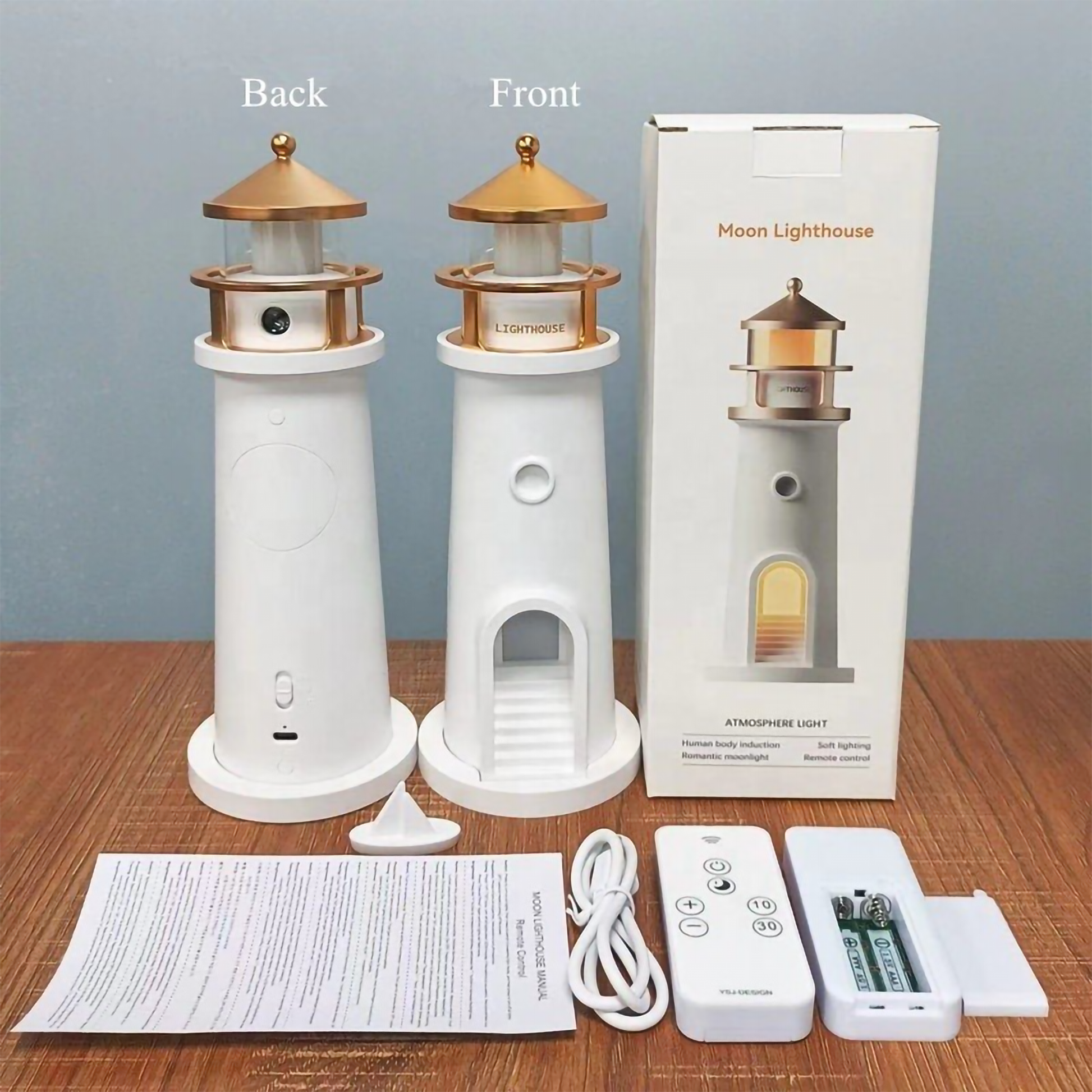 Front and back view of the white and gold Moon Lighthouse lamp alongside its retail packaging, remote control, USB cable, and manual