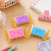 A collection of three colorful mousse cake erasers, each individually sealed in clear plastic candy wrappers with yellow zig-zag borders.