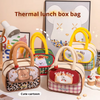 A collection of cute cartoon thermal lunch box bags in dog, bear, and fruit girl themes arranged on a table.   