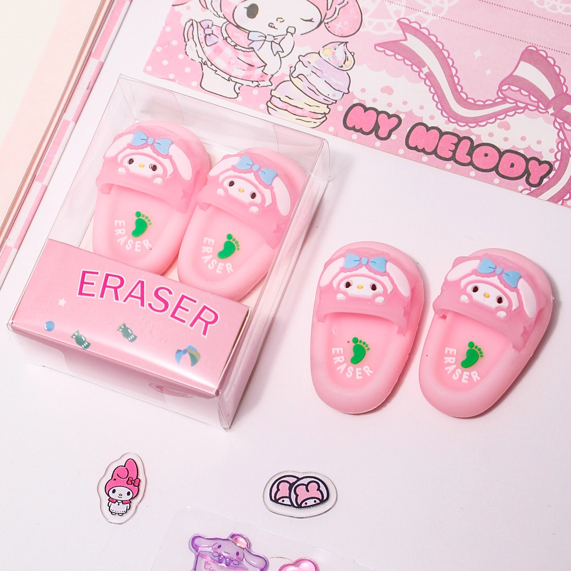 Close-up of a pink clear box showing a pair of adorable mini 3D slipper erasers with cute bunny faces on the front straps.
