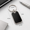 Black keychain with measurements on a white surface with office items.