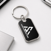 Black keychain with a silver ring on a white surface with office supplies.