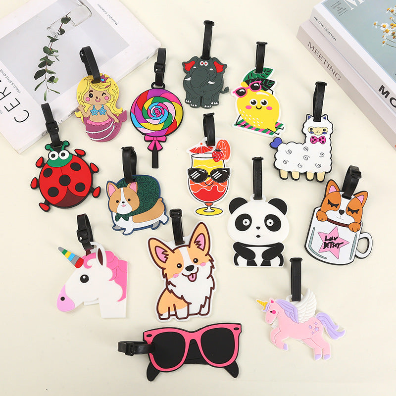 Assorted cartoon silicone luggage tags featuring cute designs like panda, dog, emoji, airplane, and food items with adjustable straps.